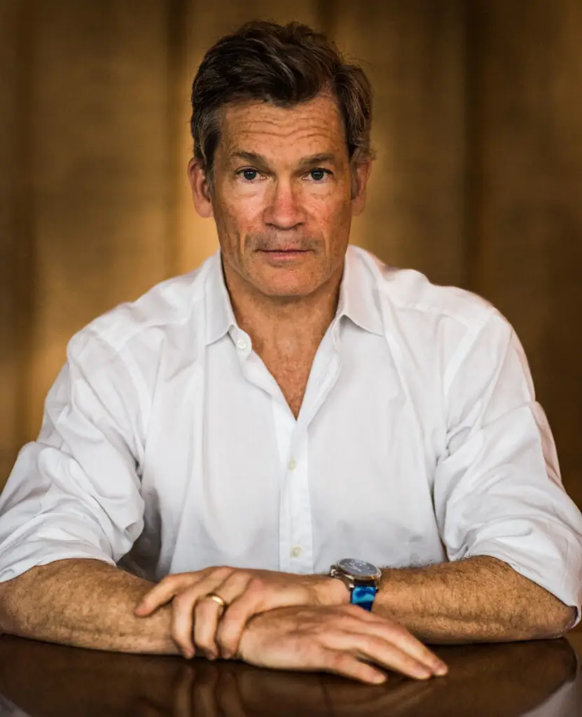 Portrait of Louis Bacon seated at a table, wearing a white dress shirt, looking directly at the camera.